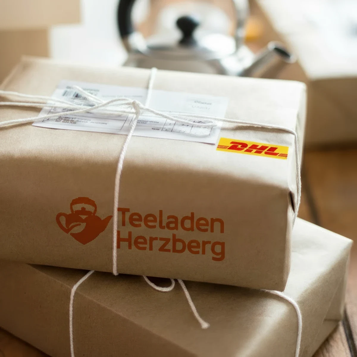 Symbolbild Versandpakete - Logo der DHL und Teeladen Herzberg beigefügt